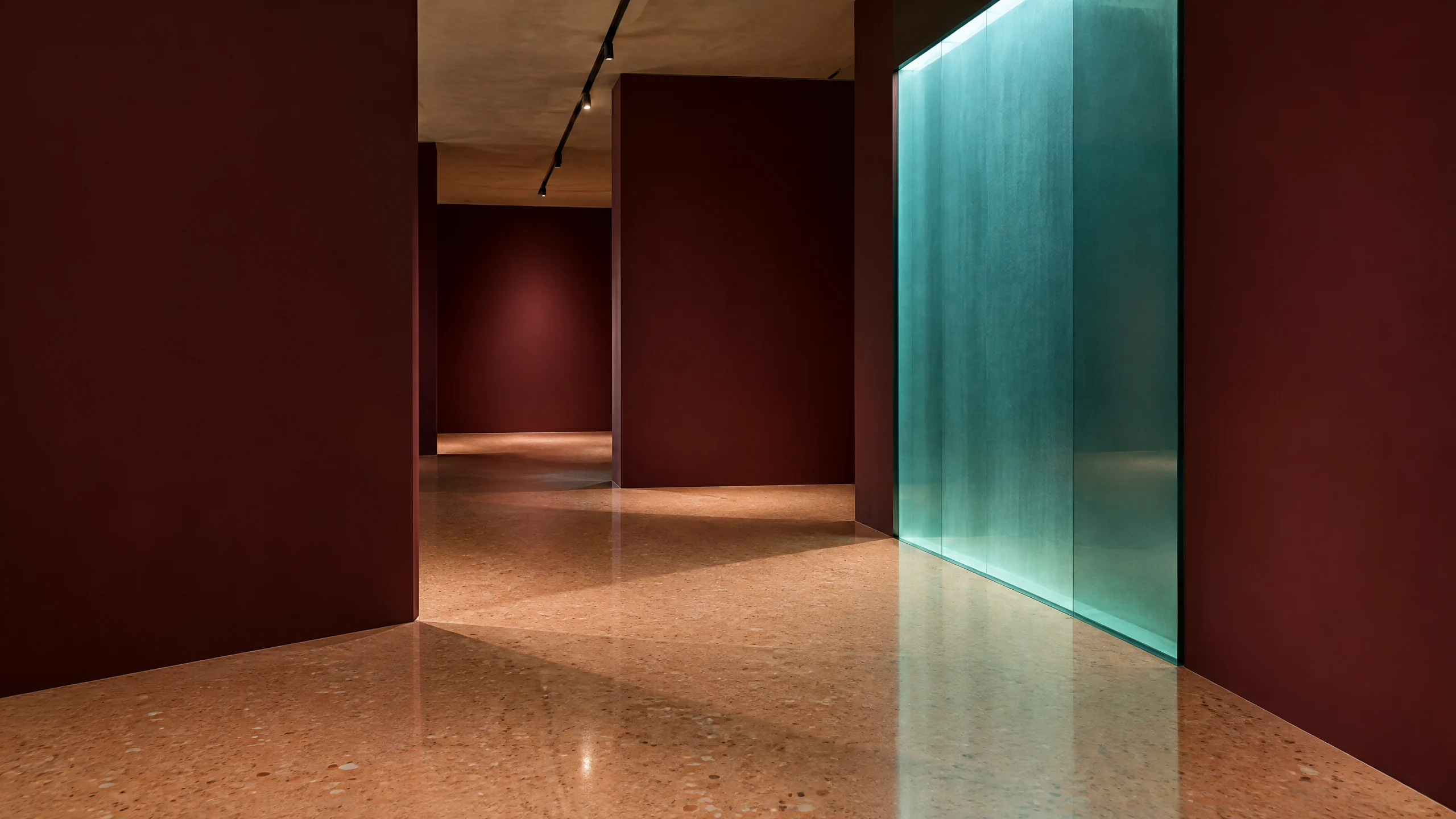 Quiet gallery passage with illuminated teal panel